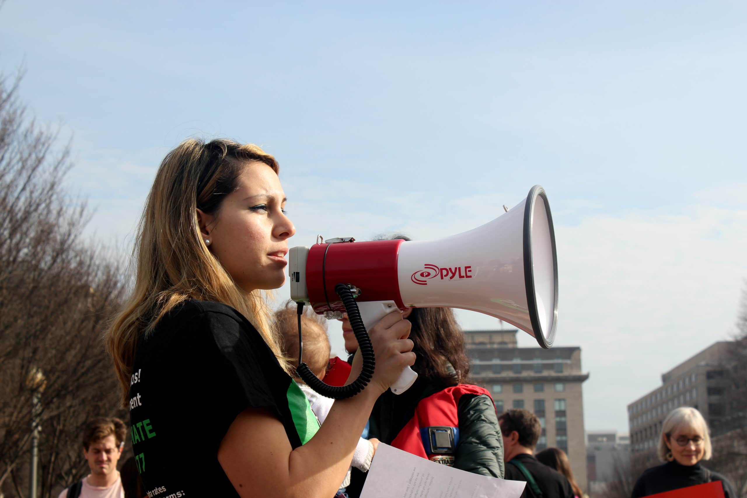 An activist speaking into a megaphone at a protest