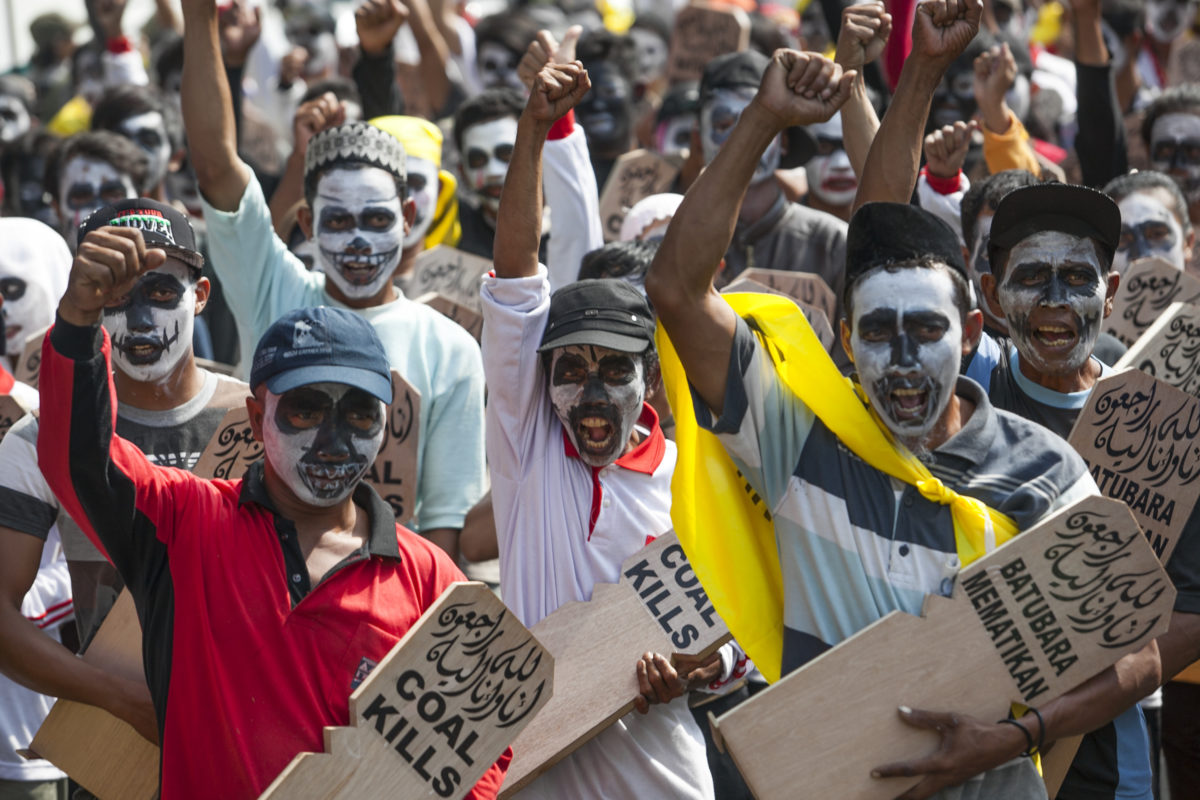 Activists marching with their faces painted like skulls and carrying signs that say "Coal Kills"
