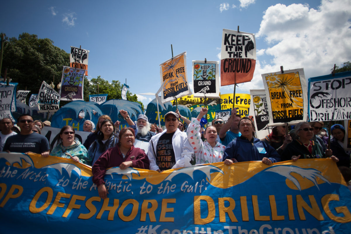 A large group of protestors carrying banners and signs against offshore drilling