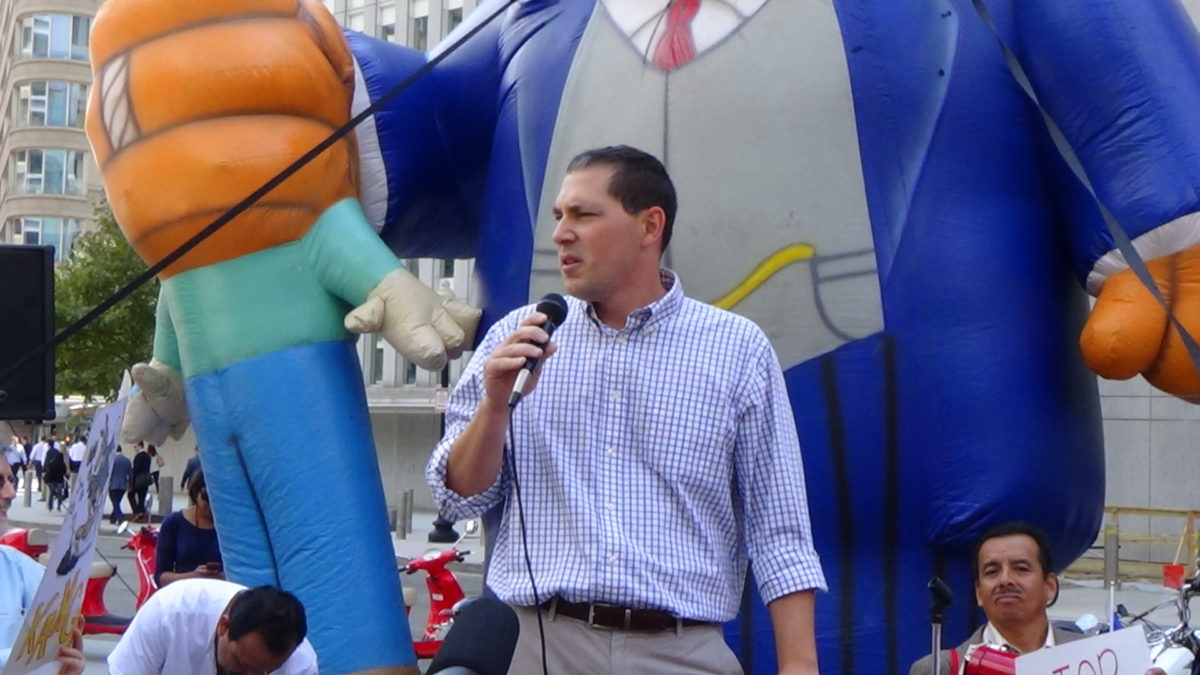 A speaker standing in front of a balloon speaking on a microphone