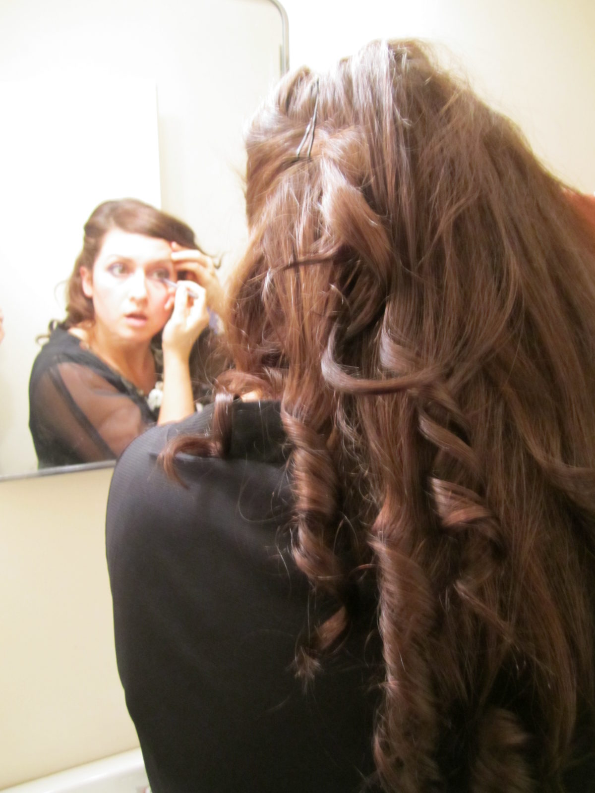 A woman putting eyeliner on in the mirror