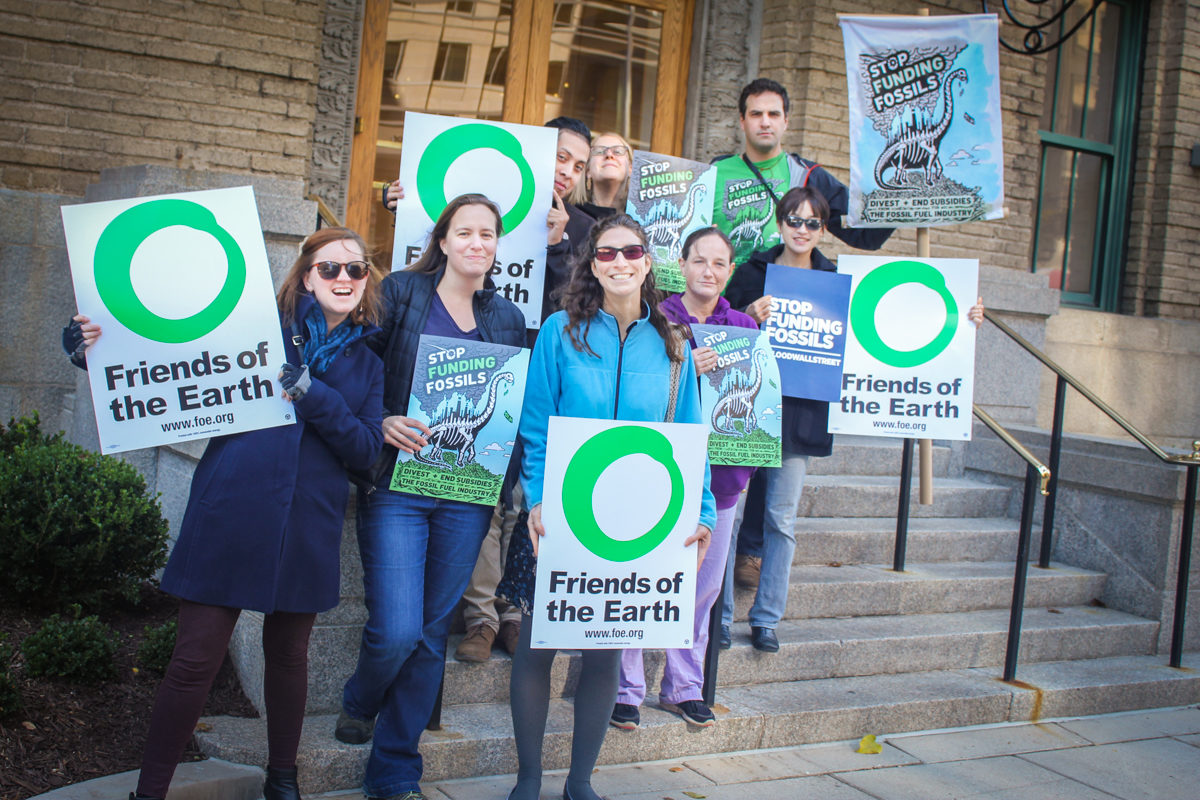 Activists holding Friends of the Earth signs and signs against funding fossil fuels