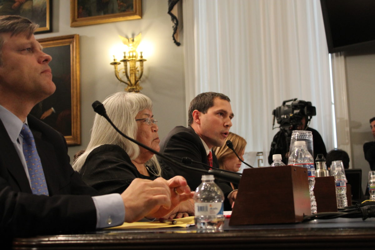 Three people sitting at a table testifying before a Congressional committee