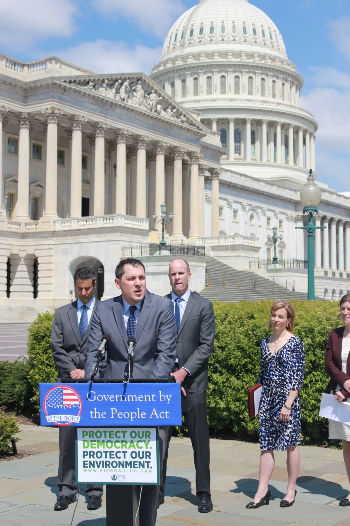A speaker standing at a podium for a press conference supporting the Government by the People Act outside of the US Capitol Building