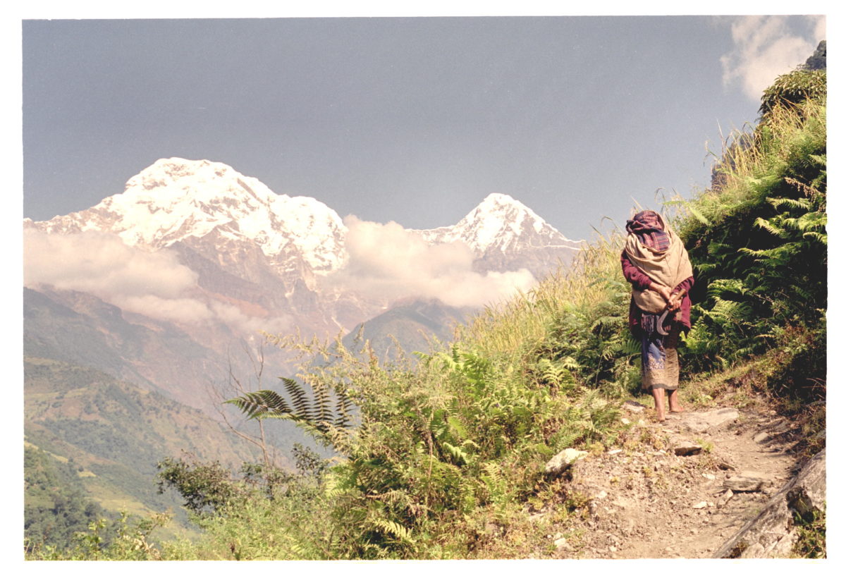 A person hiking up a trail with a mountain range in the background