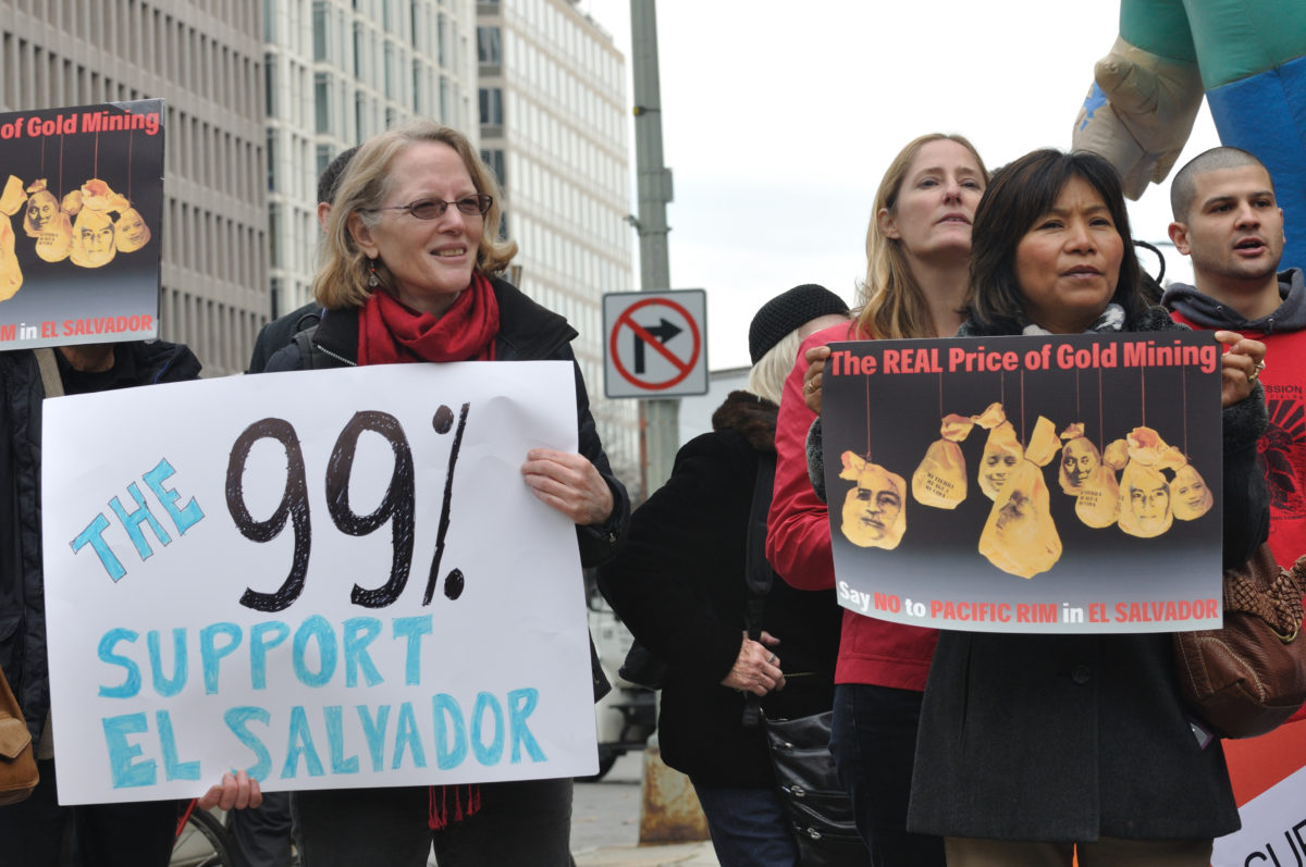 Two activist holding signs in support of gold miners in El Salvador