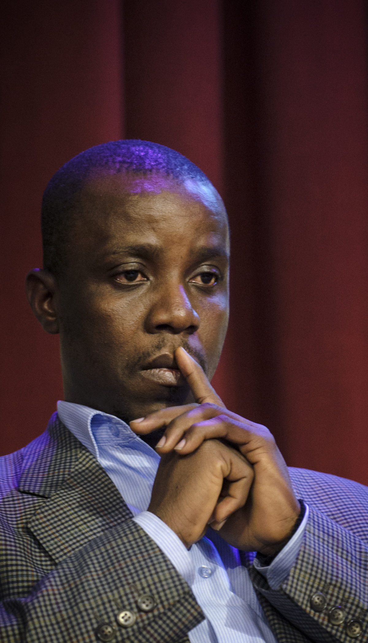 Silas Kpanan'Ayoung Siakor sitting with his hands clasped and a finger to his lips