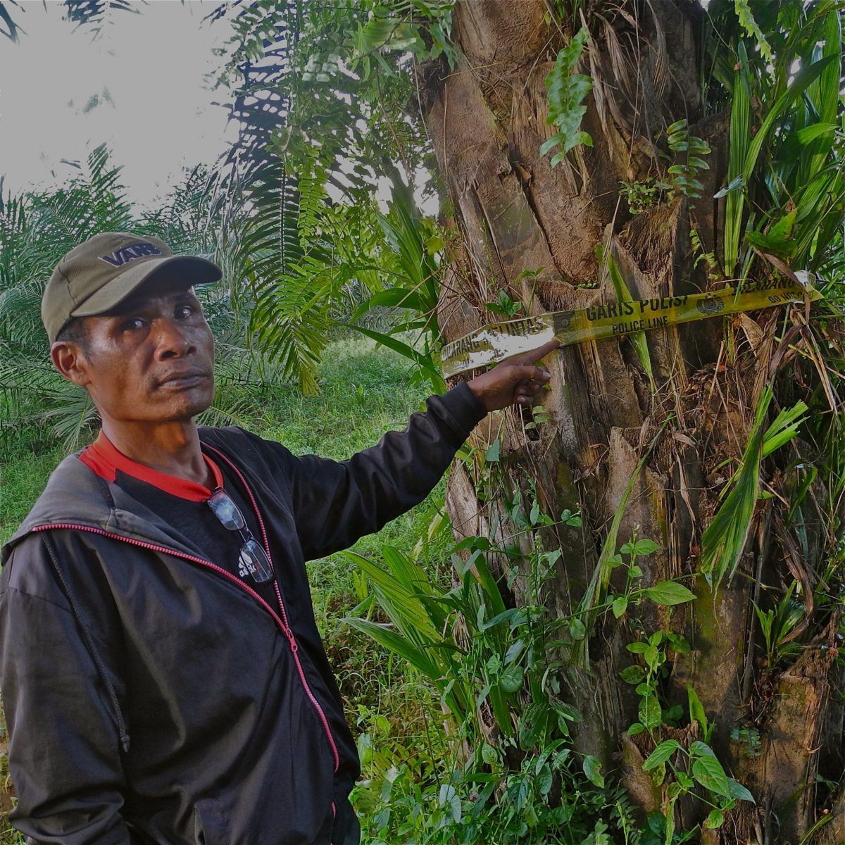 A man standing and pointing at police tape tied around a tree