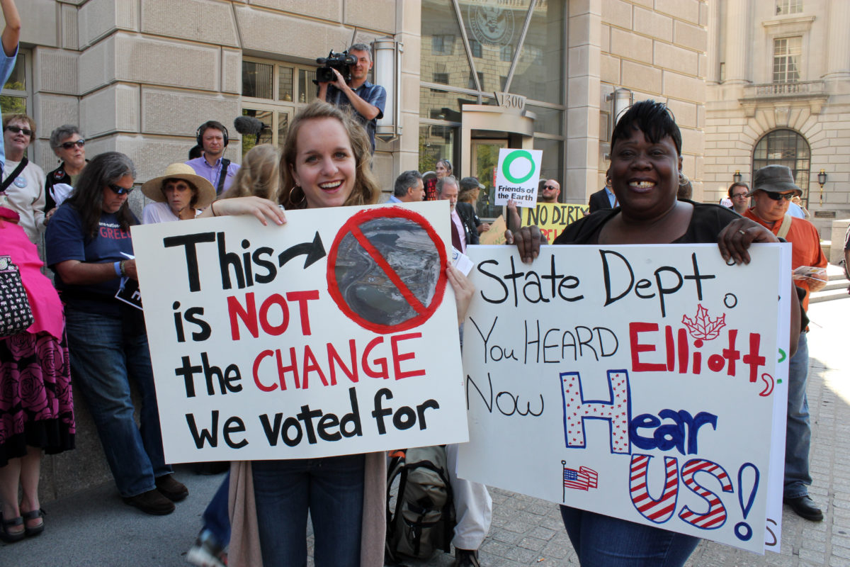 Two protestors holding signs against Keystone Pipeline