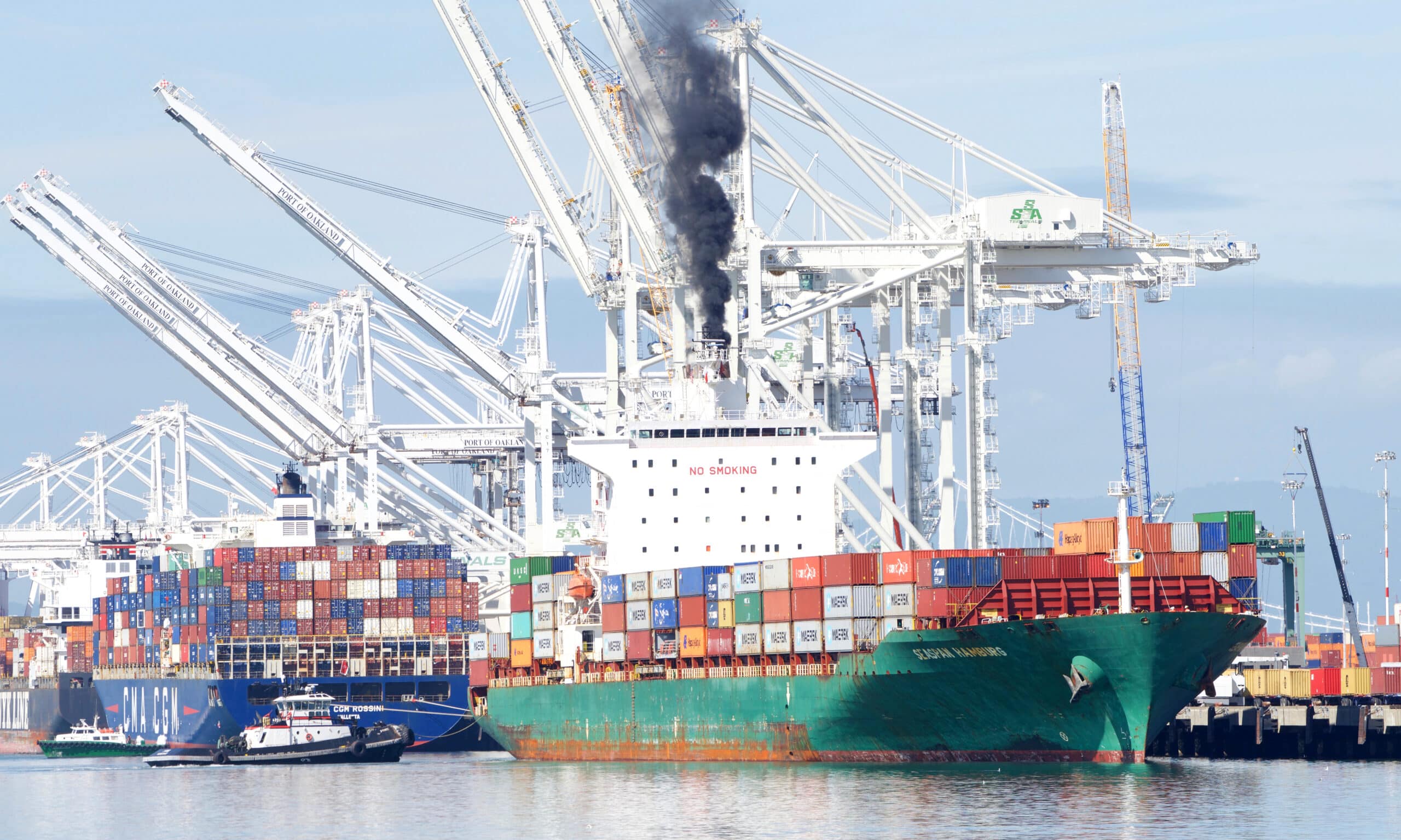 May contain two cargo ships and cranes at a port.