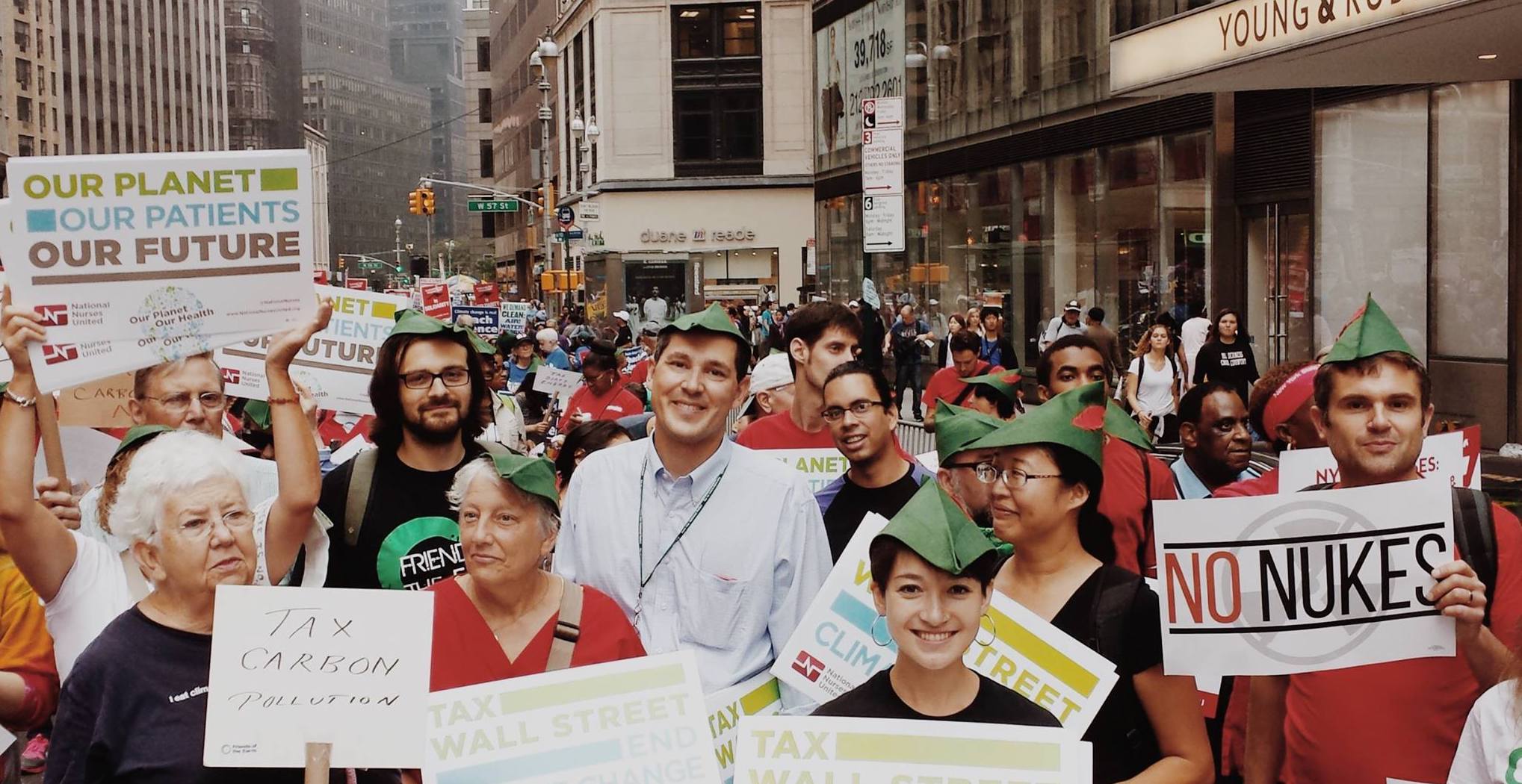 Activists in a large group with Robin Hood hats on holding signs about climate change