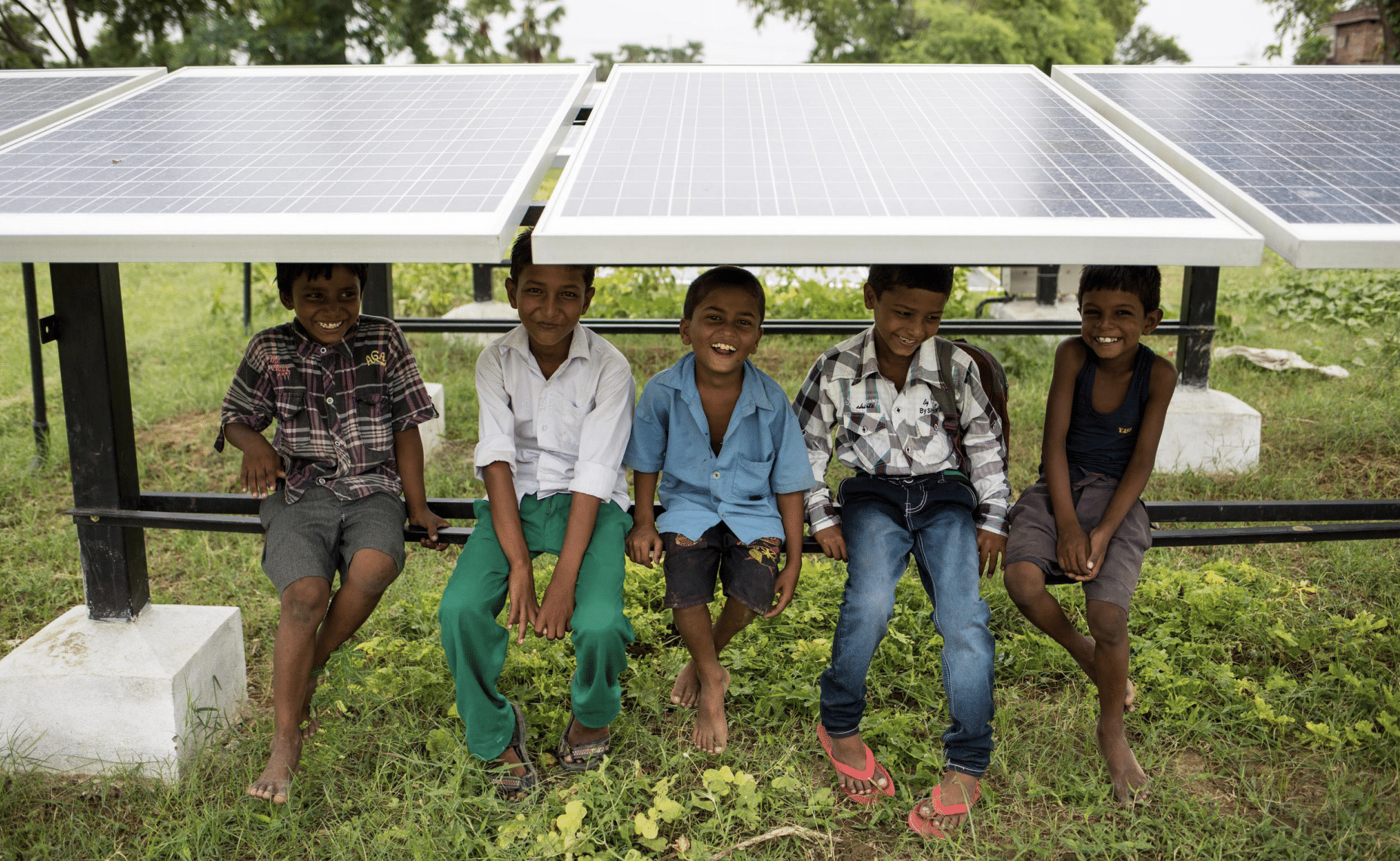 Five children sitting underneath a solar panel