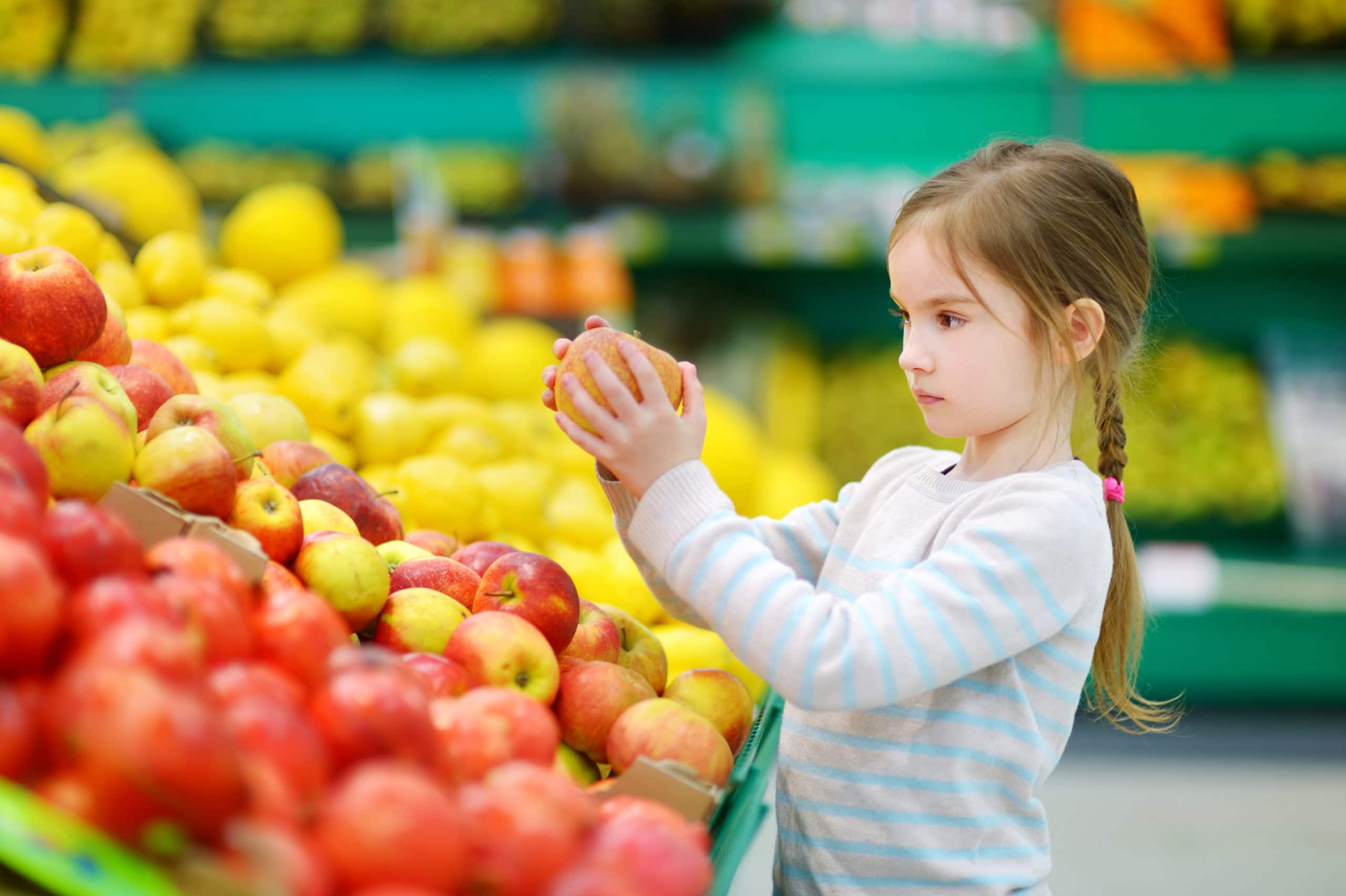 Child holding orange in supermarket