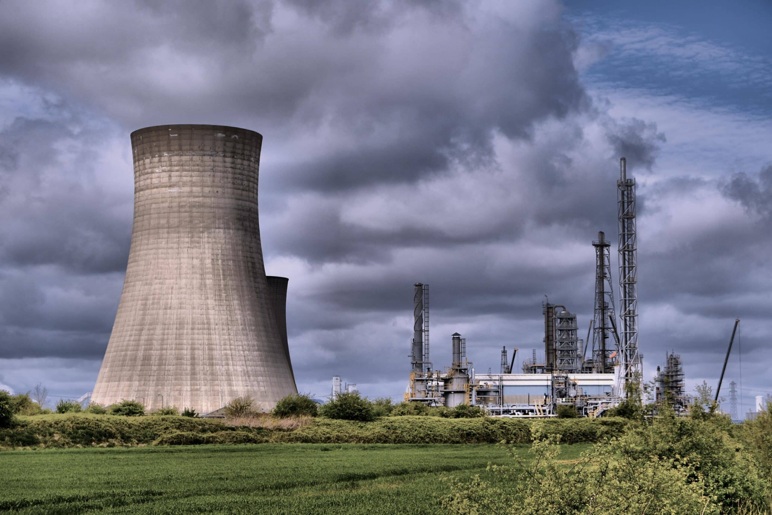 May contain a cooling tower and industrial plant under a cloudy sky.
