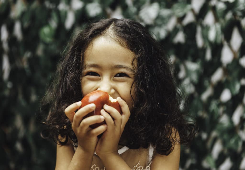 A young girl eating an apple