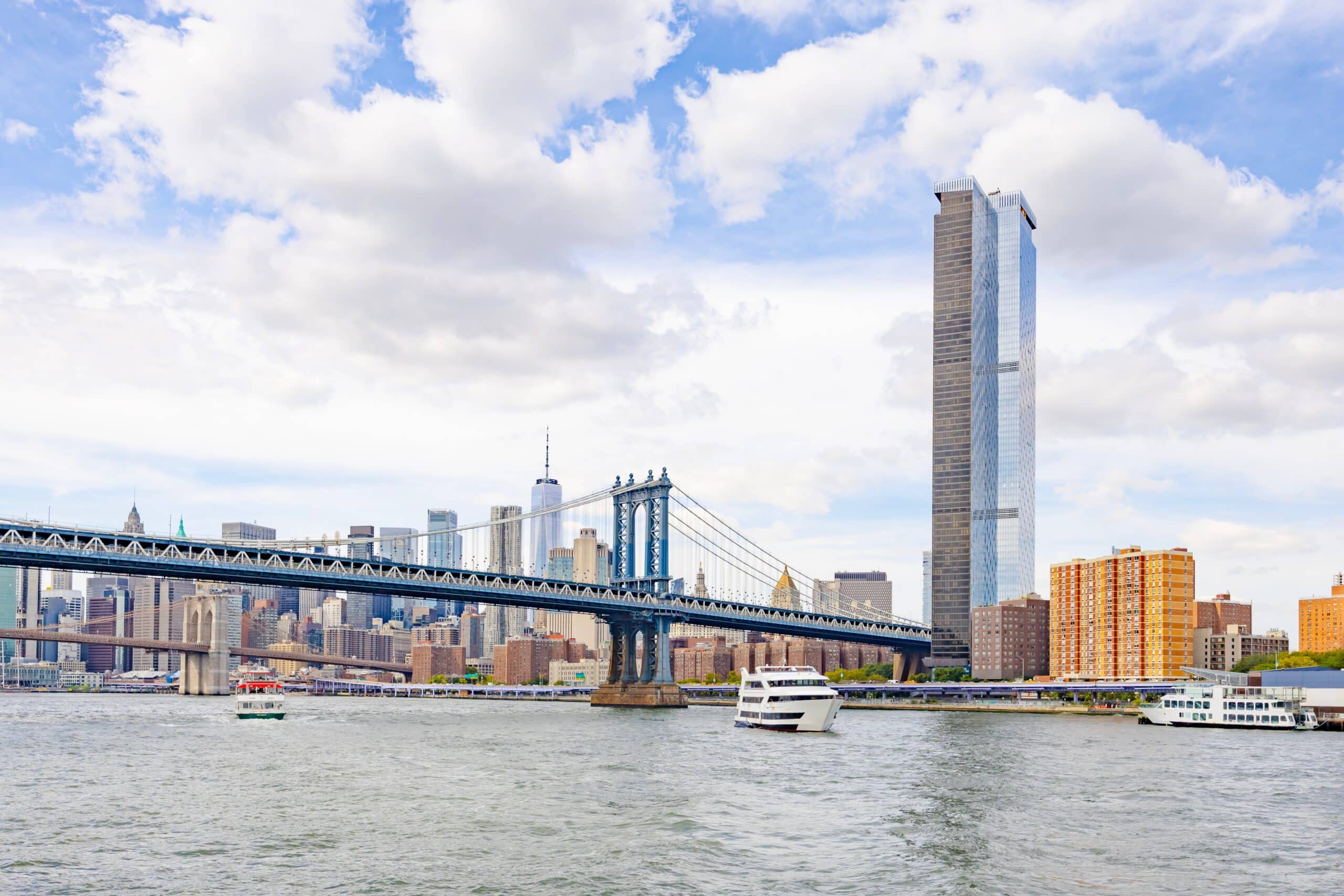 May contain two boats on the water with a bridge and city skyline.