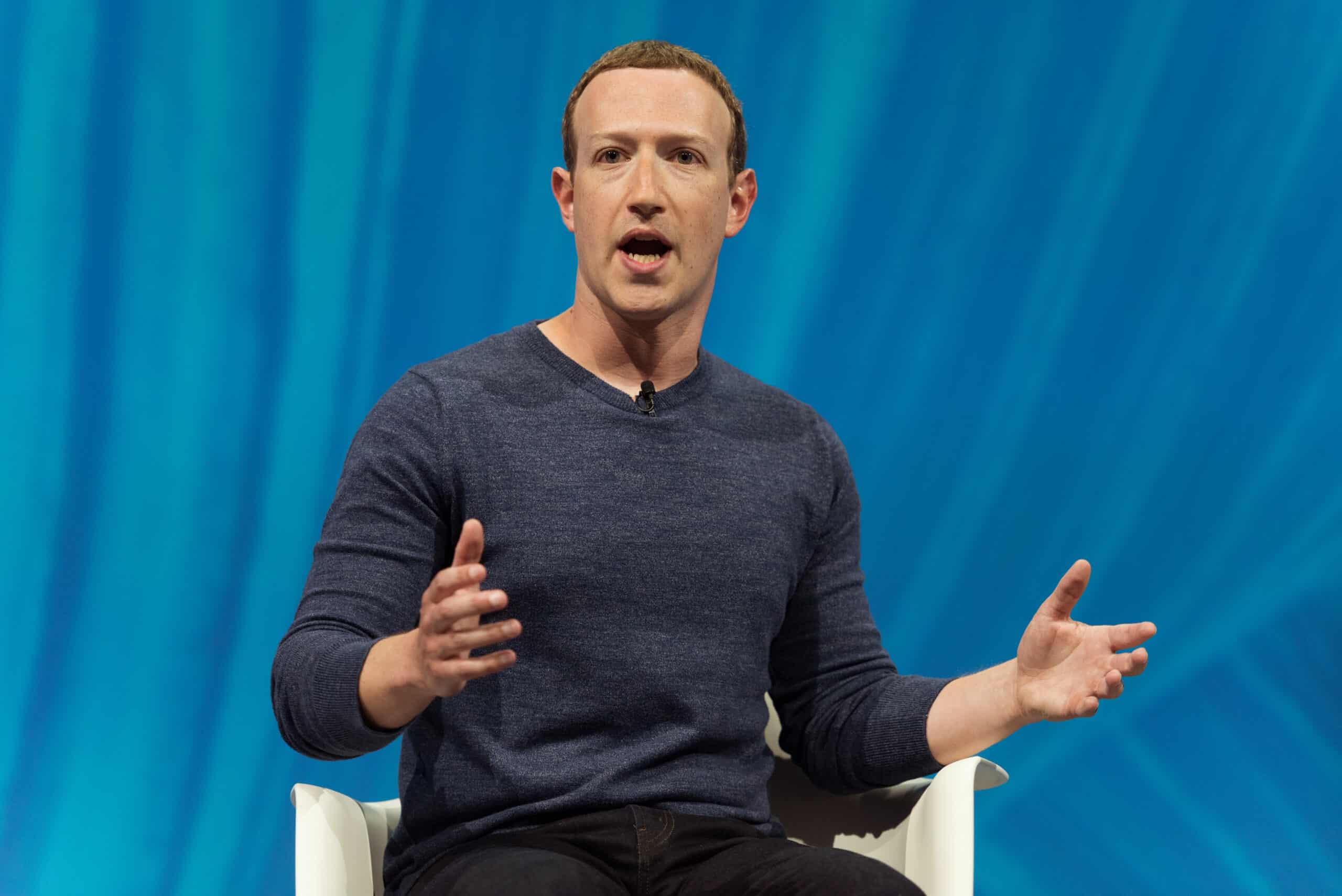 May contain one person speaking with hands gesturing on a blue background.