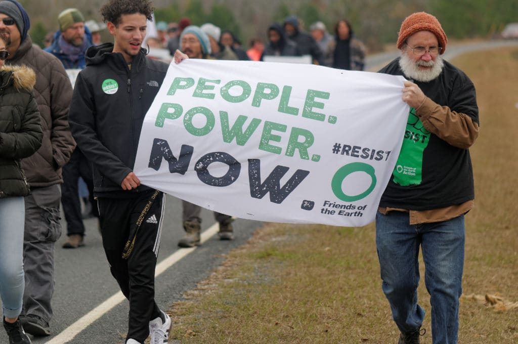 Protesters Holding a People. Power. Now #Resist Friend's of the Earth Banner