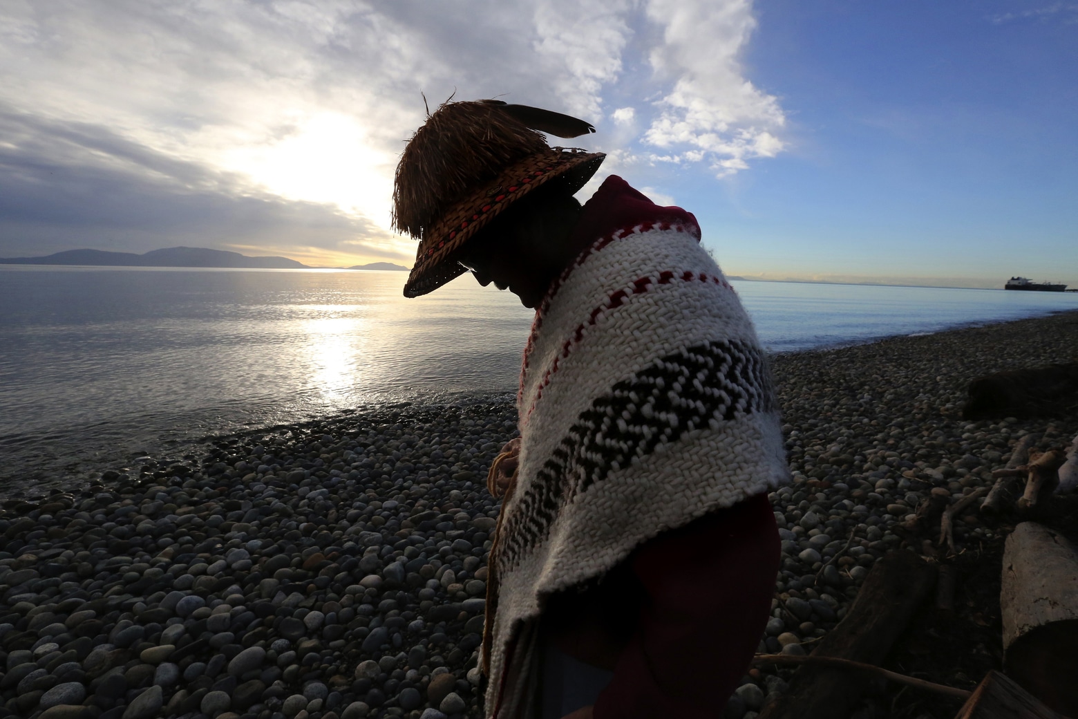 A person standing on a stone laden beach along the ocean