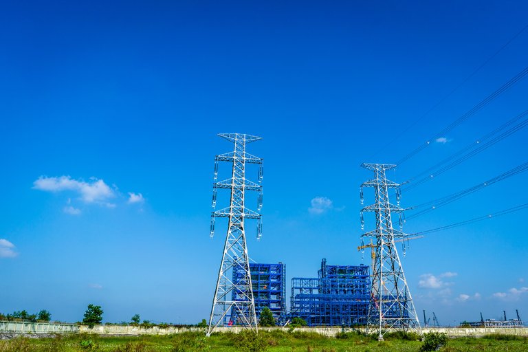 Electrical Towers in a field with blue scaffolding in the background