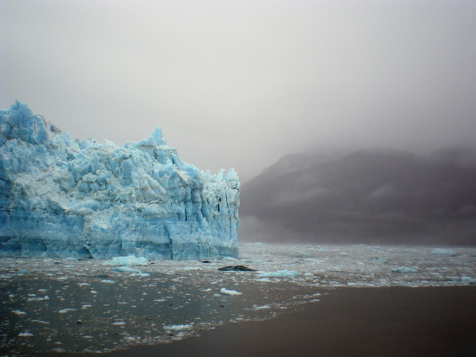 Blue Glacier Amongst Foggy, Grey Sky, Sea and Water