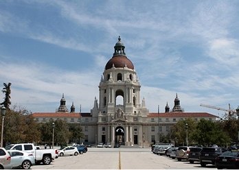 A large building with a domed roof and a row of parked cars.