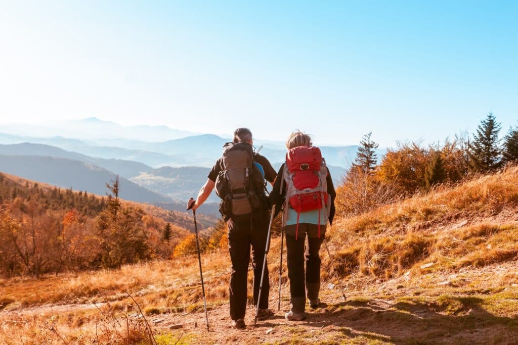 May contain two people hiking with backpacks and trekking poles.