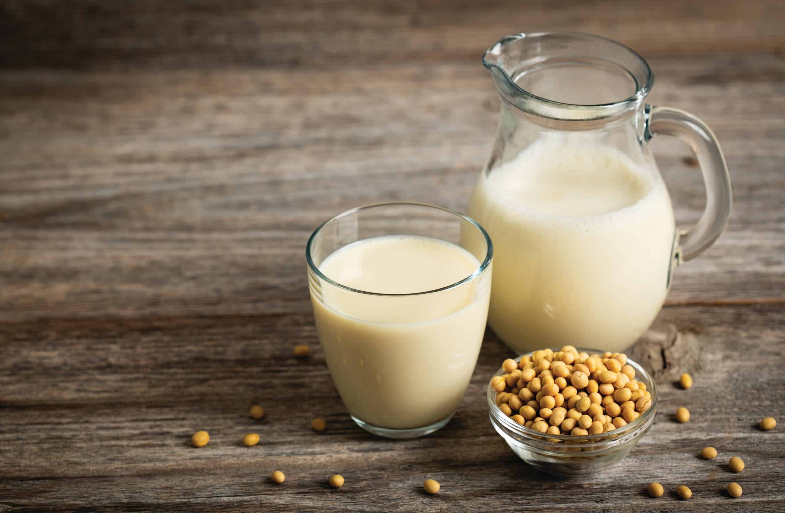 May contain soy milk in a glass and pitcher, with soybeans in a bowl.