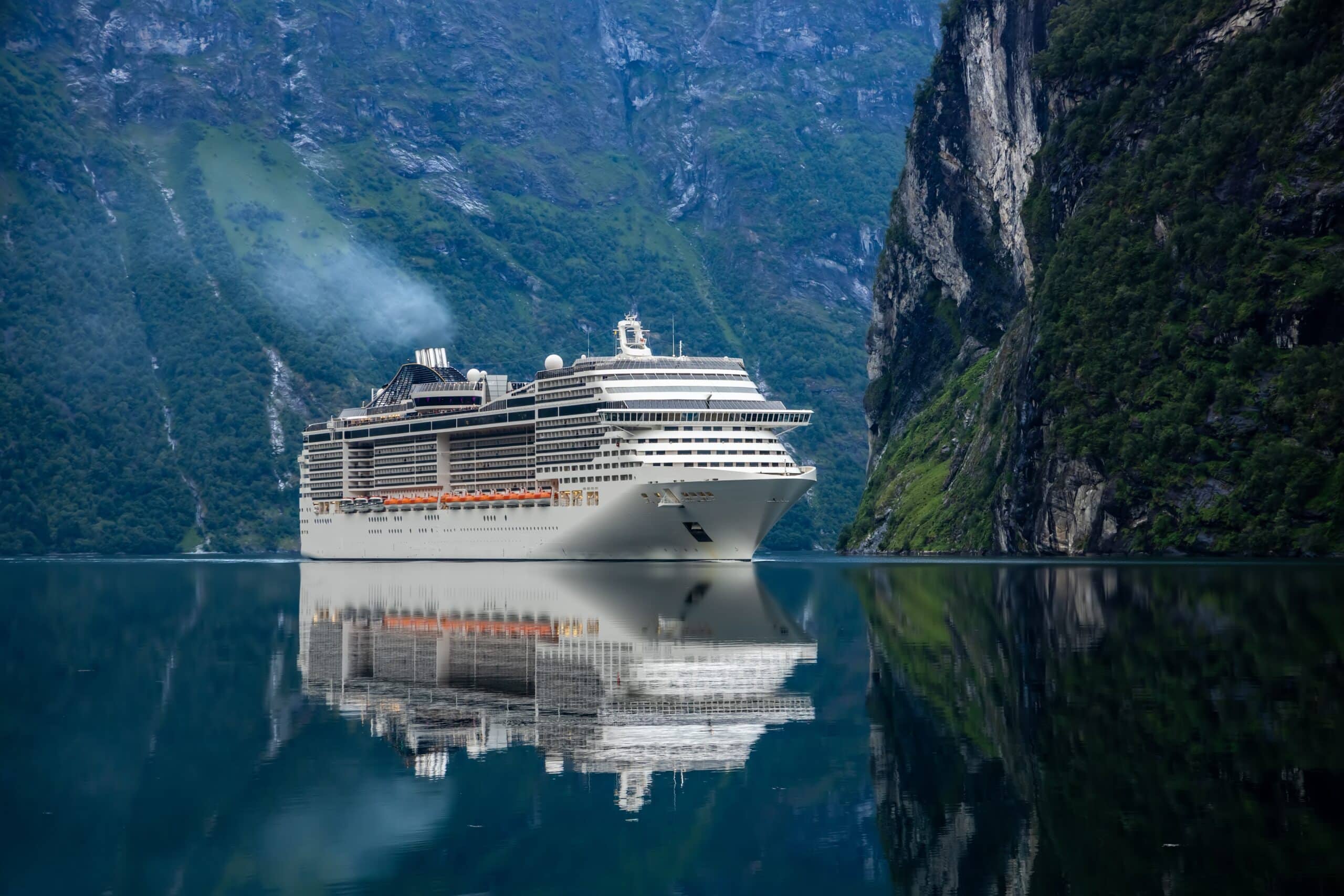 May contain a cruise ship sailing on dark water with reflections.