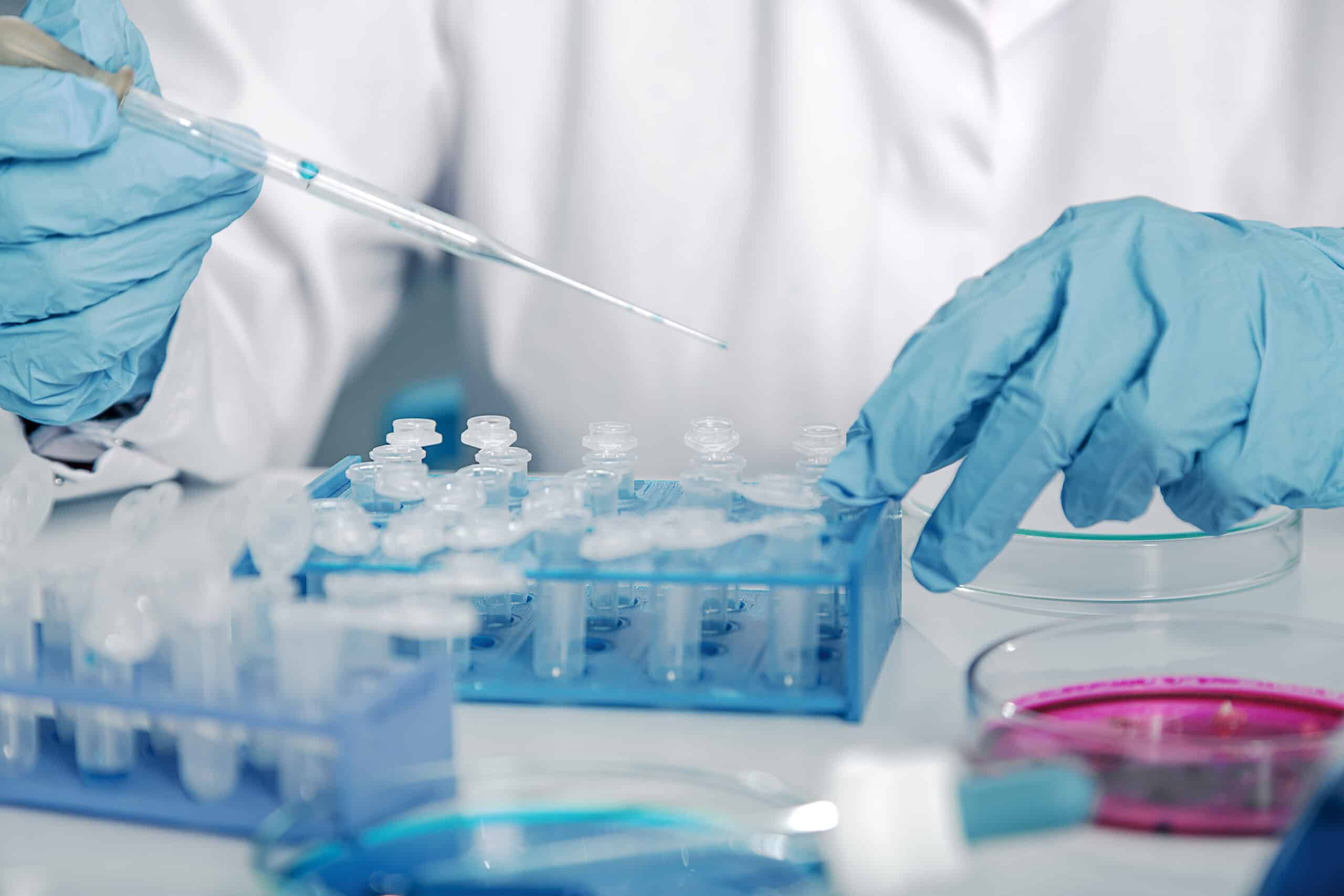May contain one person in blue gloves using a pipette in a lab.