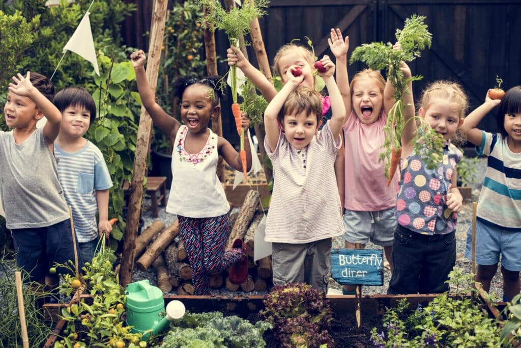 May contain eight smiling people holding fresh produce.
