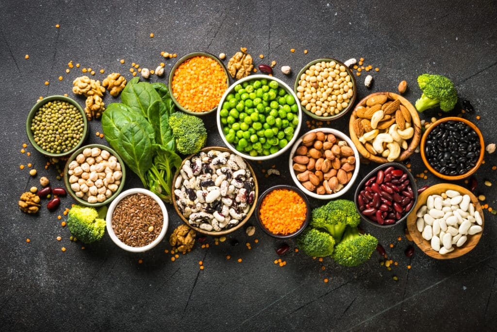 May contain bowls of assorted beans, nuts, lentils, peas, flaxseed, broccoli, and spinach.