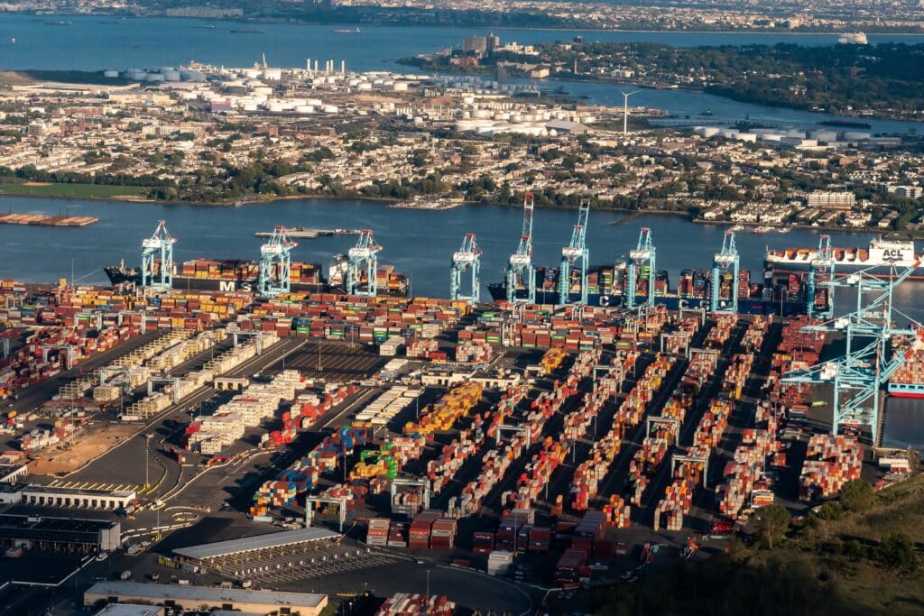 May contain an aerial view of a busy shipping port with stacks of colorful containers.