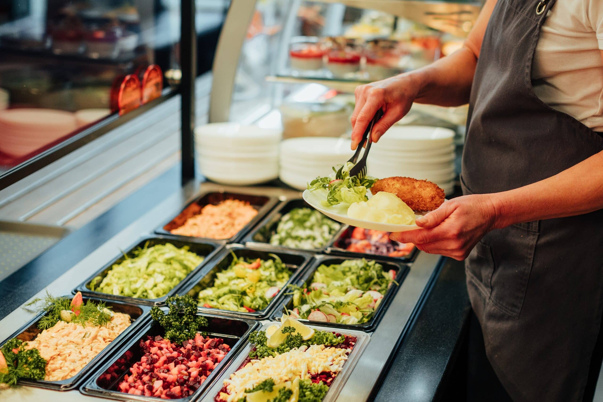 May contain a person serving a catered meal of mashed potatoes, a fried cutlet and salad.