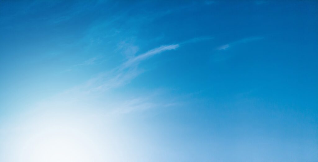 May contain a bright sun on the left with thin clouds in a blue sky.