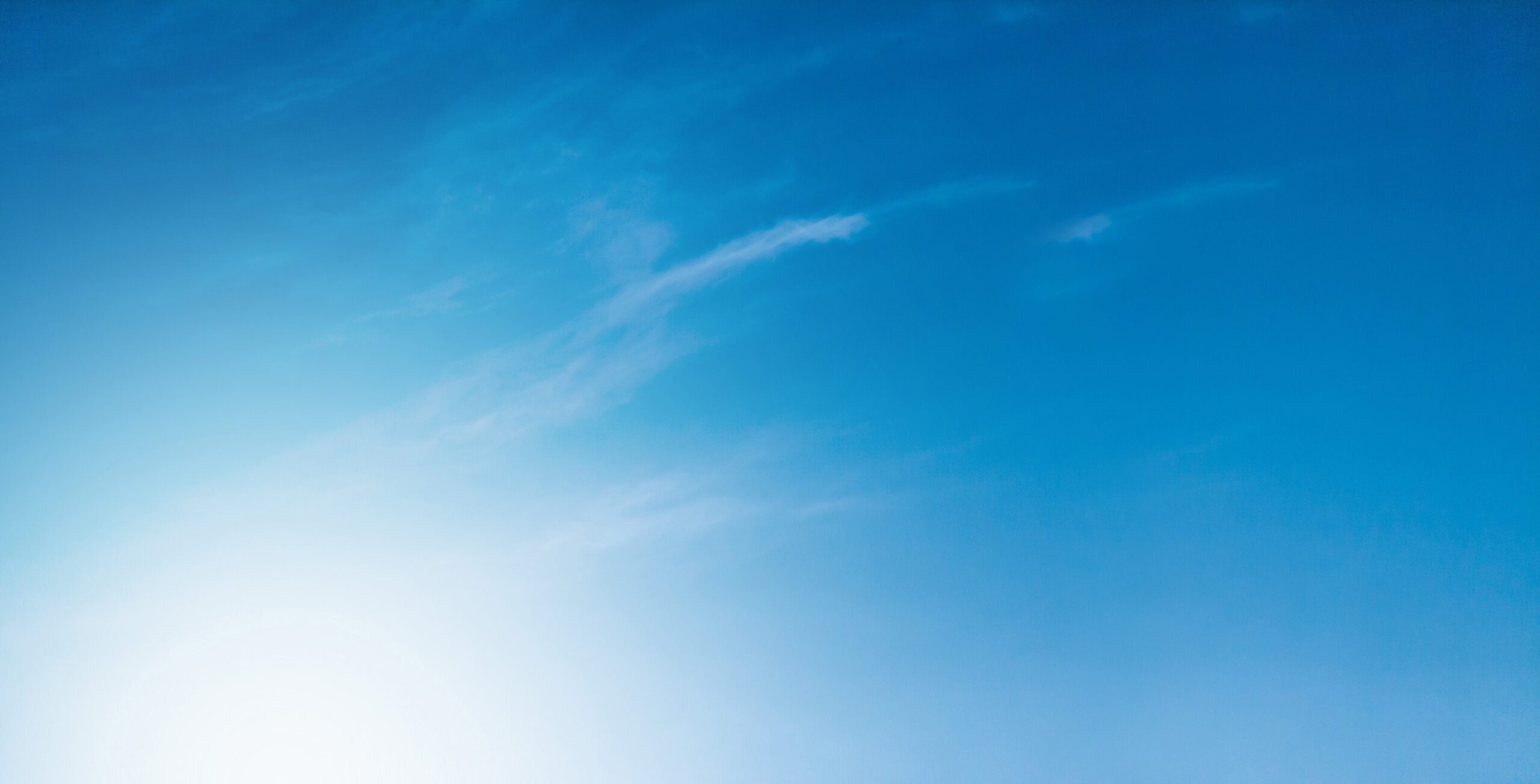 May contain a bright sun on the left with thin clouds in a blue sky.