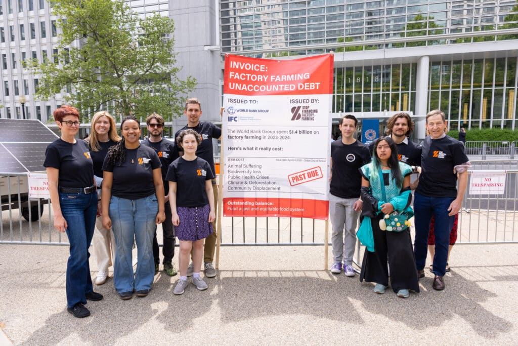May contain nine people standing near a banner and solar panels.