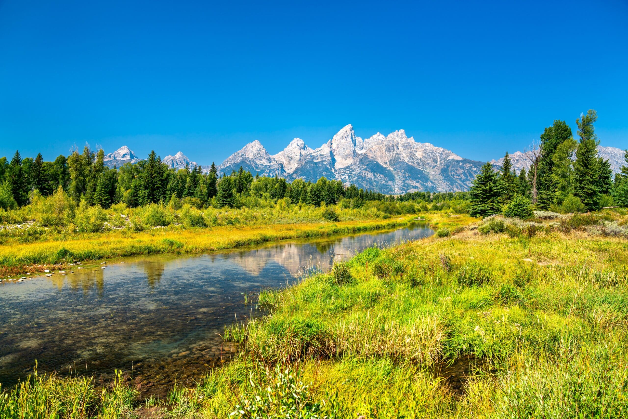 May contain a wide river with mountains reflected in it.