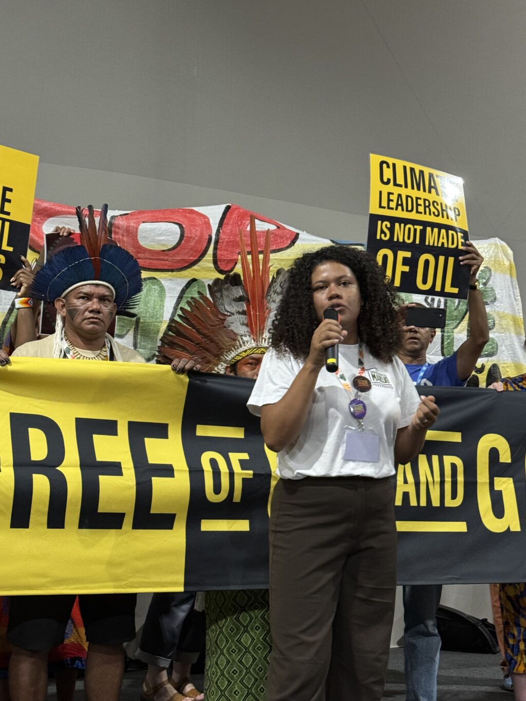 May contain a person speaking into a microphone, and other people holding signs and banners.
