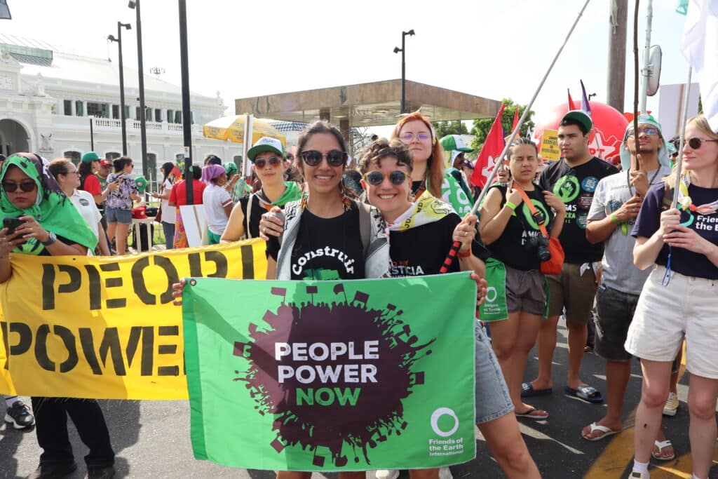 May contain several people holding a yellow banner that says "PEOPLE POWER" and a green banner.