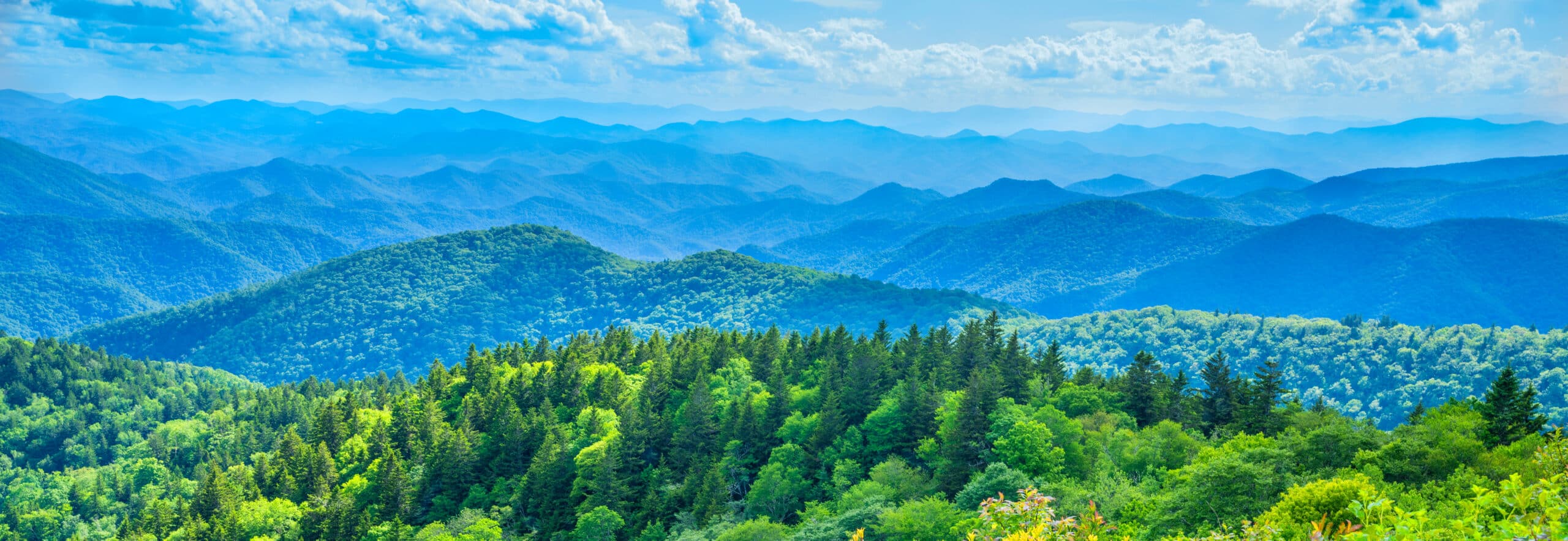 May contain rolling green mountains under a blue sky with clouds.