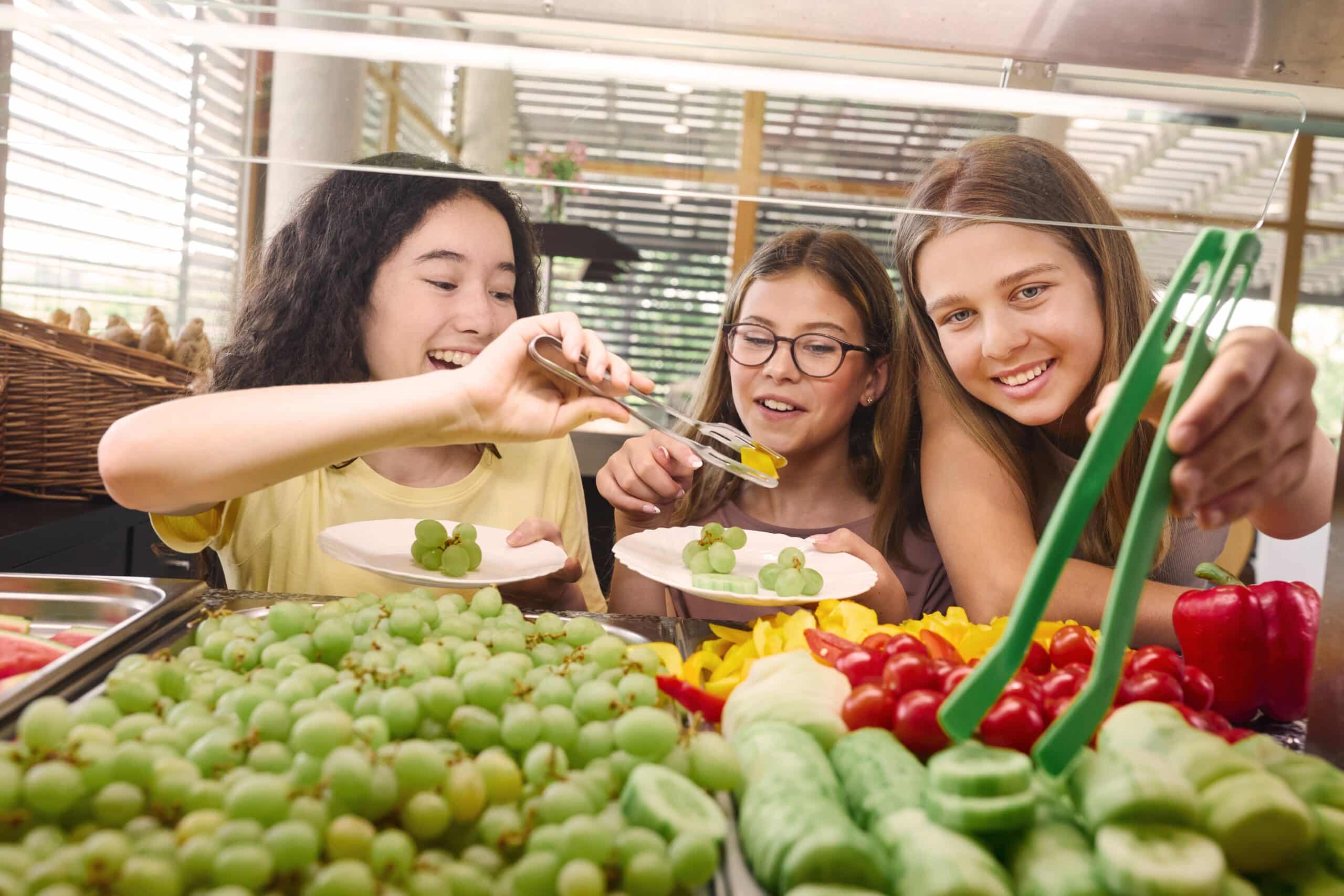 May contain three people choosing fruit from a buffet.