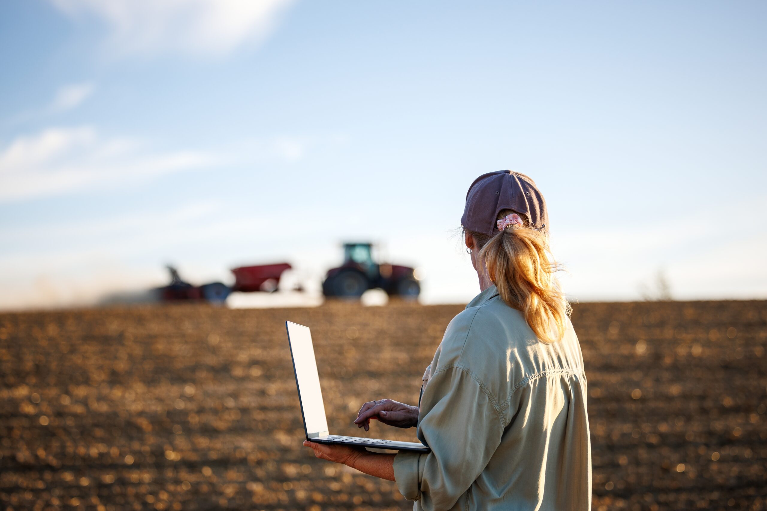 May contain a person using a laptop in a field with tractors.